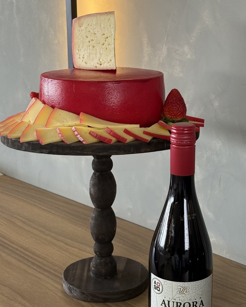 Aurora Pinot Noir ao lado de queijo em bandeja de madeira